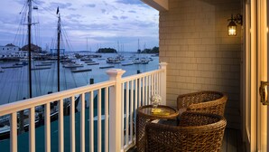 Een balkon met rieten stoelen en een tafel, met uitzicht op een jachthaven met boten.