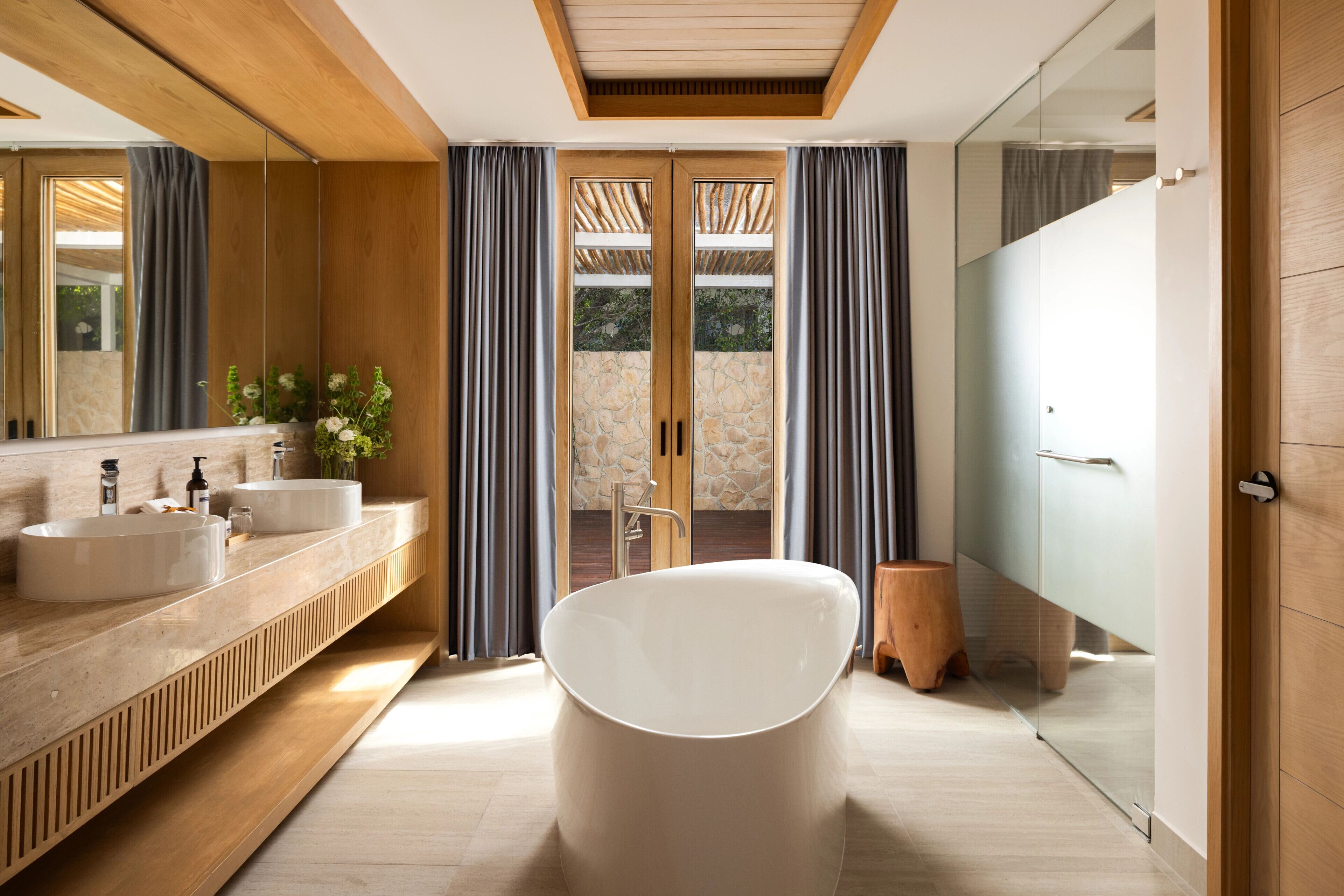 A modern bathroom with a freestanding bathtub, dual sinks, and a large mirror.