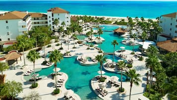 A resort with multiple swimming pools, palm trees, and beachfront views.