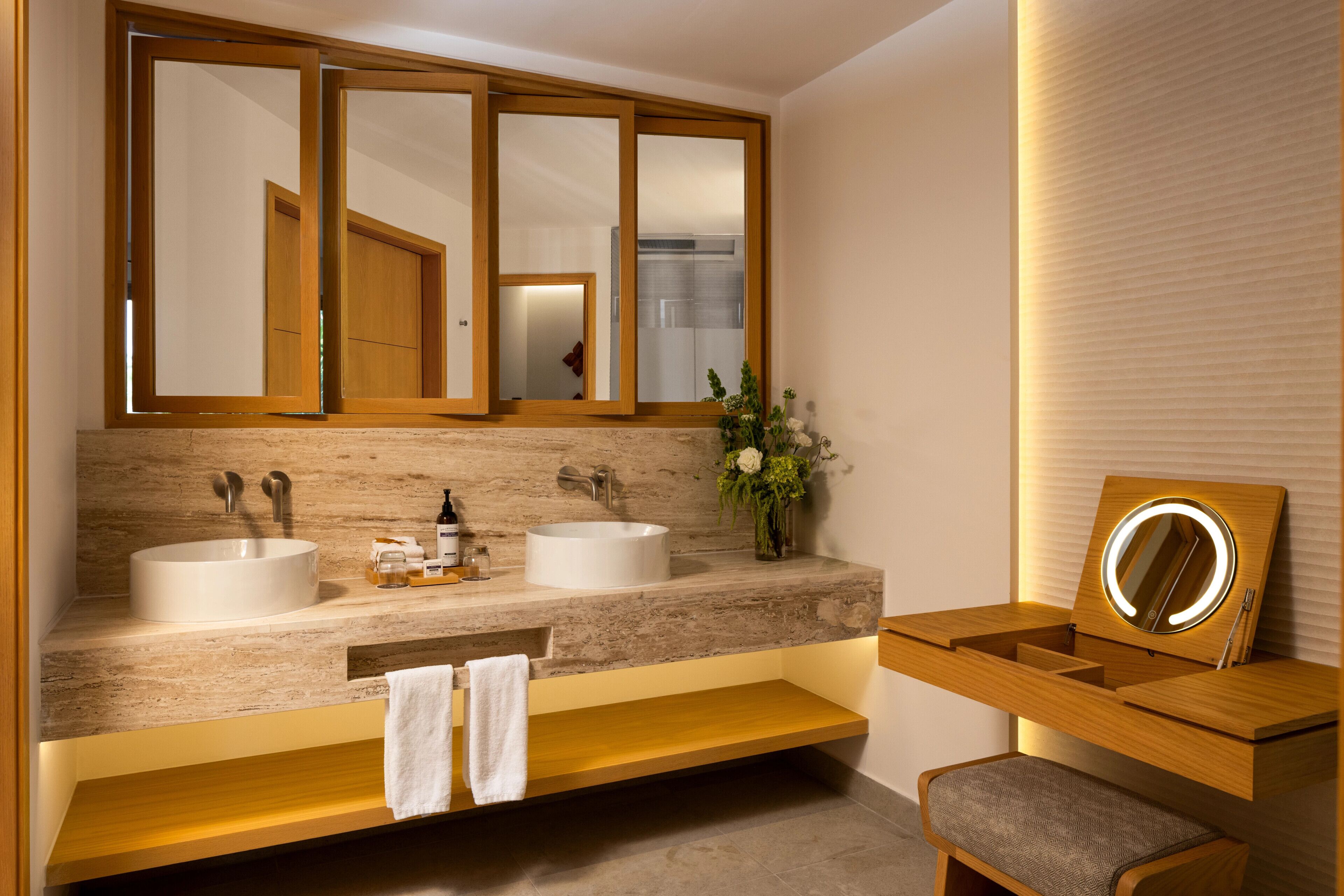 A modern bathroom with two sinks, a vanity with a mirror, and a towel rack.