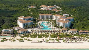 An aerial view of a resort with multiple buildings, a central pool, and a beach.
