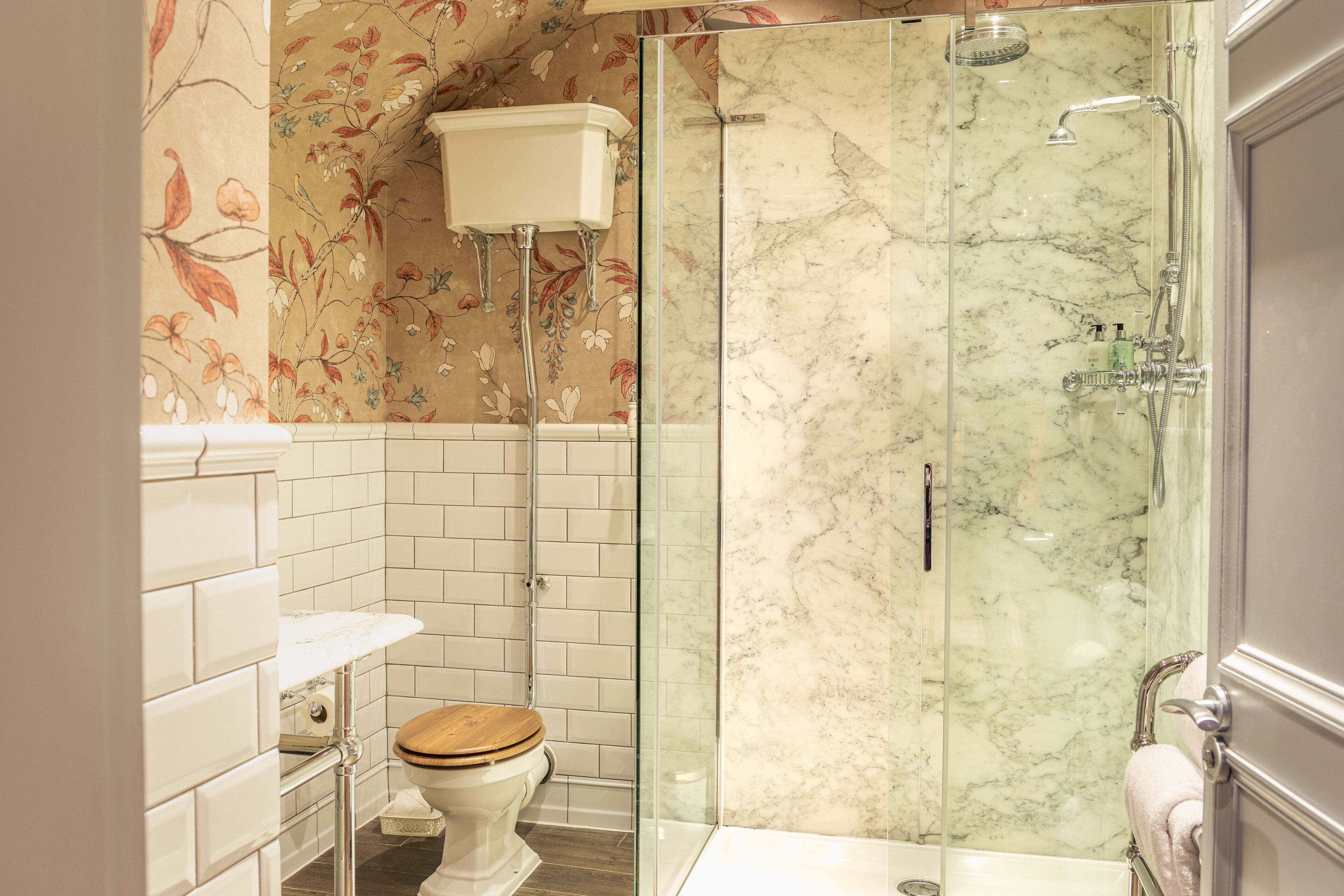Un baño con inodoro, ducha de vidrio y pared de mármol.