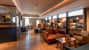 A spacious lobby with a bar area, seating arrangements, and a well-lit interior. - The Raeburn (Edinburgh)