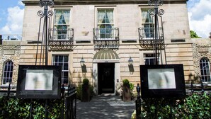 A historic building with a central entrance, two balconies with wrought iron railings, and a sign above the entrance. - The Raeburn (Edinburgh)