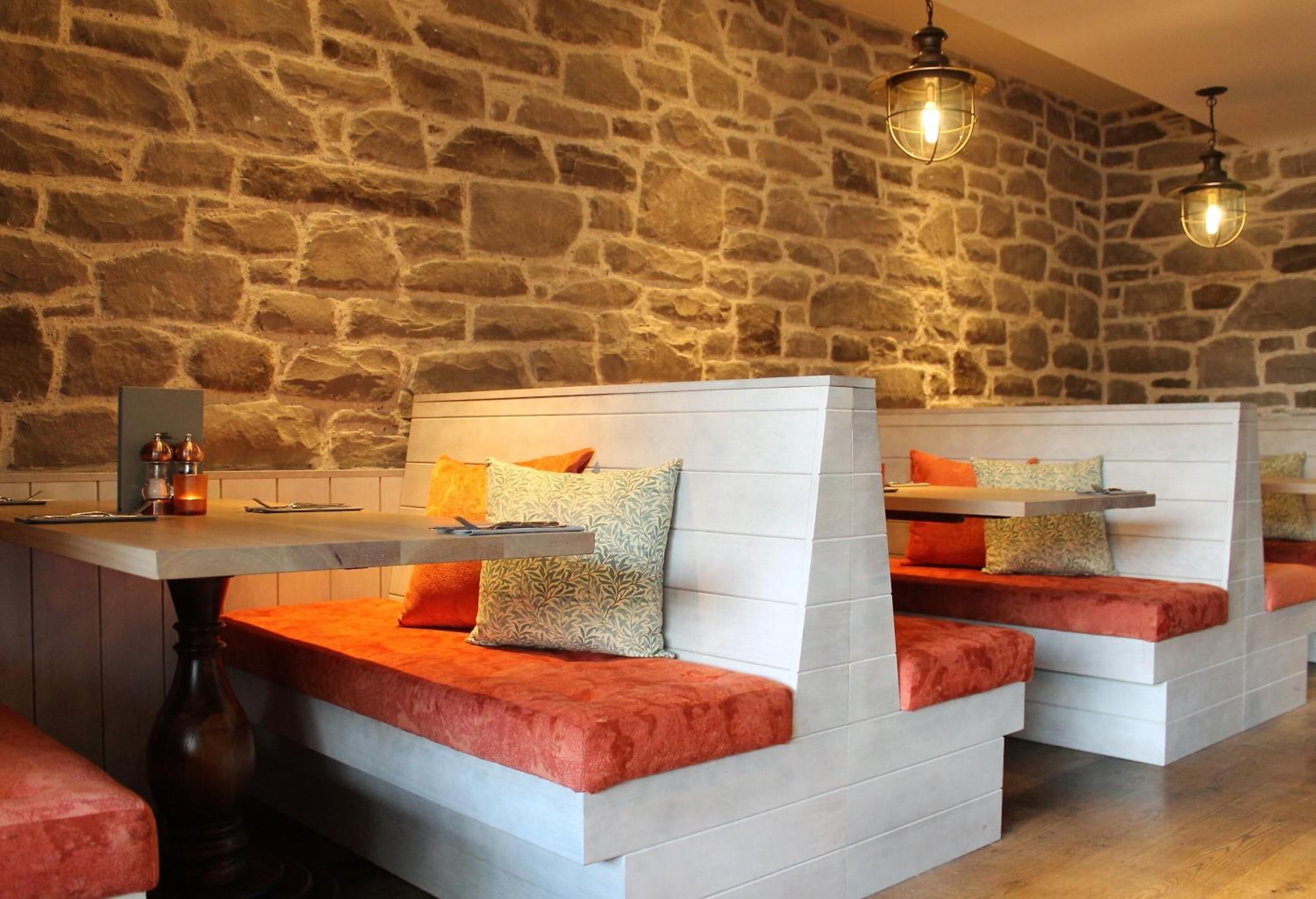 Un restaurant aux murs de pierre et aux sièges rembourrés.
