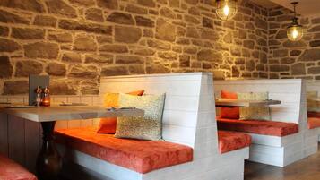 Un restaurant aux murs de pierre et aux sièges rembourrés.