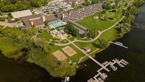 Vue aérienne d’un complexe hôtelier doté d’une piscine, de courts de tennis et d’un quai avec des bateaux.