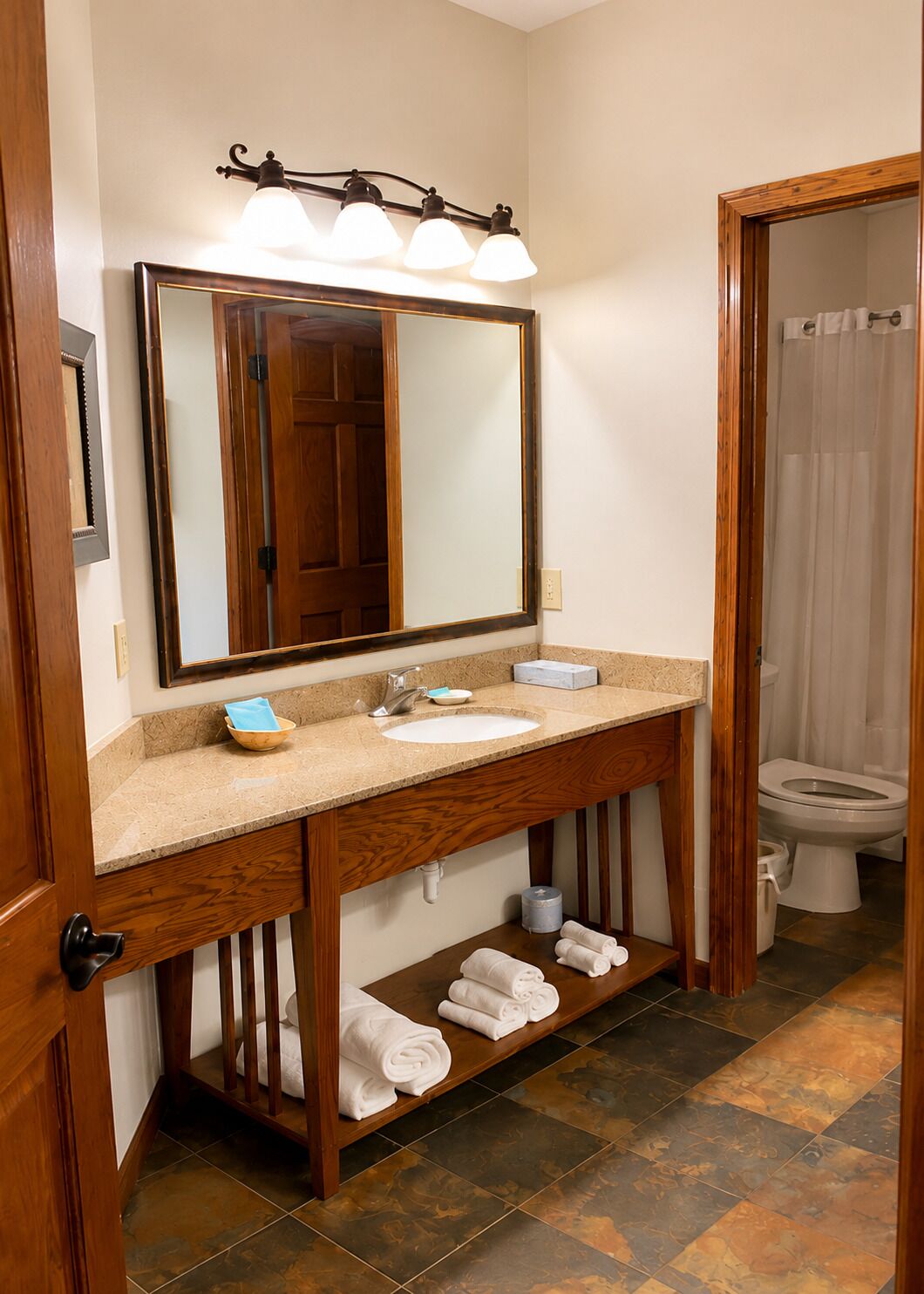 A bathroom with a wooden vanity, a large mirror, a sink, and a toilet.