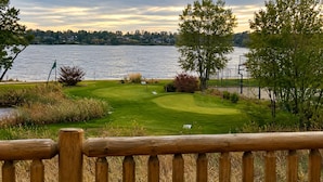 Un parcours de golf avec un plan d’eau en arrière-plan, entouré d’arbres et d’une clôture en bois.