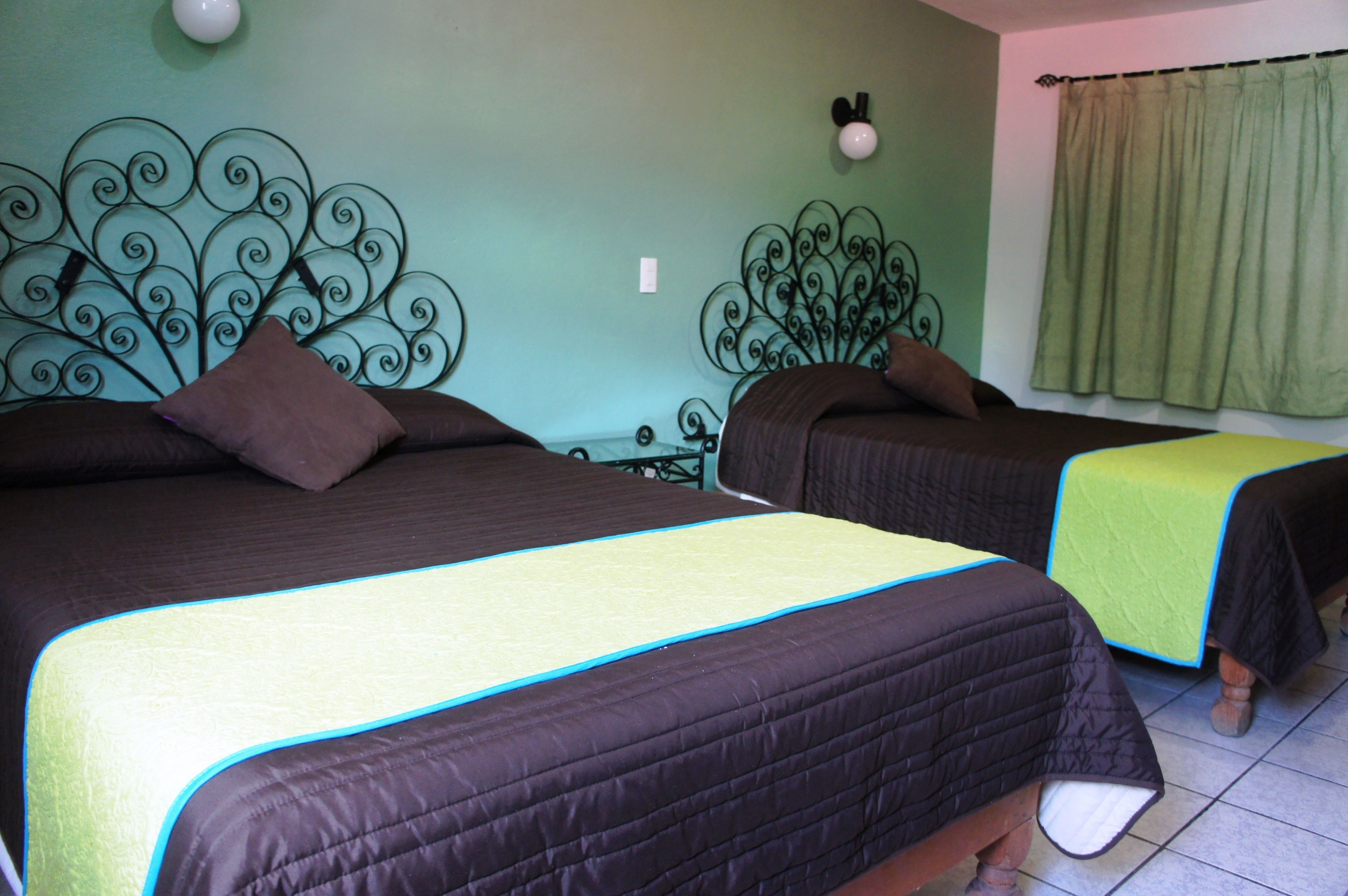 A room with two beds, each with a headboard and a pillow.