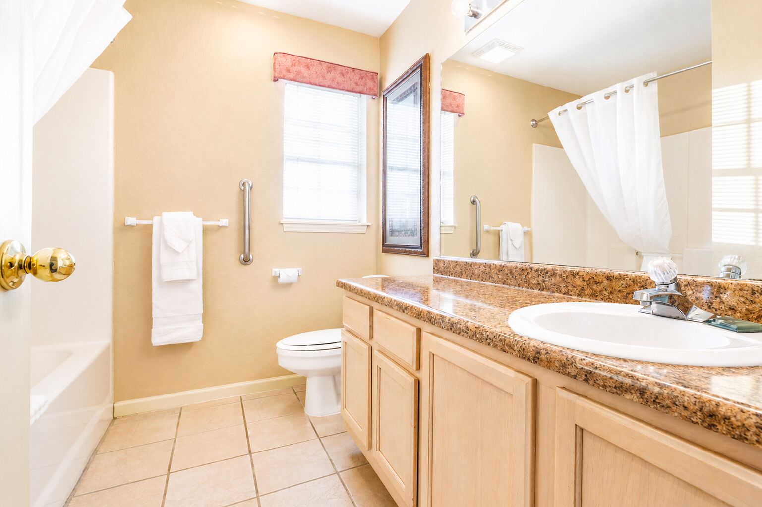 Une salle de bain comprenant des toilettes, un lavabo, un meuble-lavabo et un miroir.