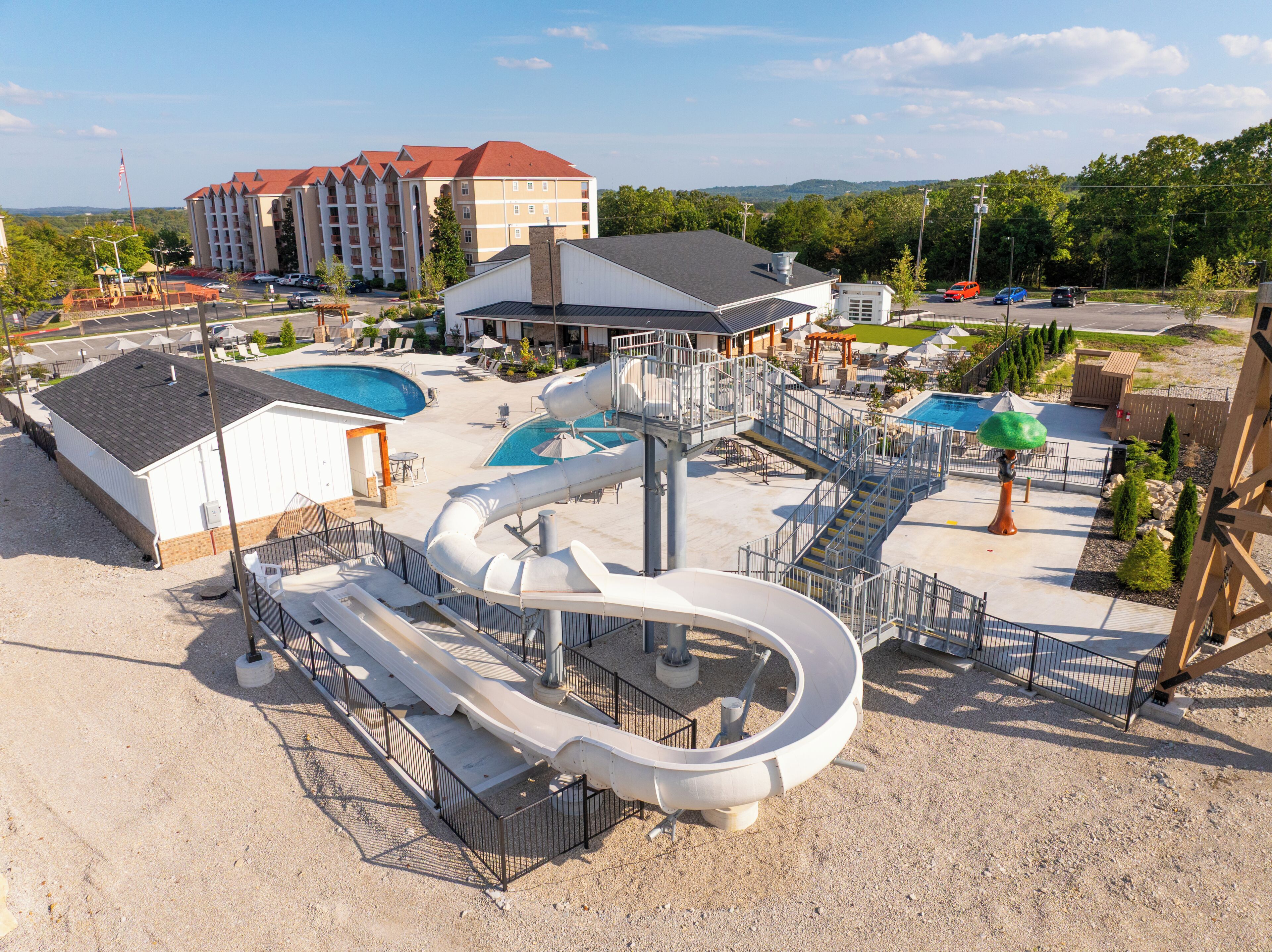 A water park with multiple slides and pools, a large building in the background, and a clear sky.