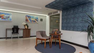 A reception area with two chairs, a small table, and a vase of flowers.
