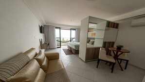 A hotel room with a sofa, a small table with chairs, a bed, a balcony with a view, and a TV mounted on the wall. - Nobile Inn Cabo Branco (João Pessoa)