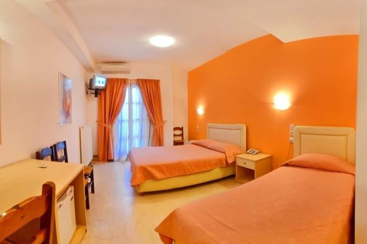 A hotel room with two beds, a desk, and a television.