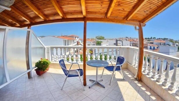 A covered outdoor area with a table and chairs, a potted plant, and a view of the cityscape. - Aretousa Hotel (Skiathos)