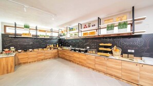 A modern kitchen with wooden cabinets, a chalkboard wall, and various food items displayed on shelves. - Aretousa Hotel (Skiathos)