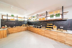 A modern kitchen with wooden cabinets, a chalkboard wall, and various food items displayed on shelves. - Aretousa Hotel (Skiathos)