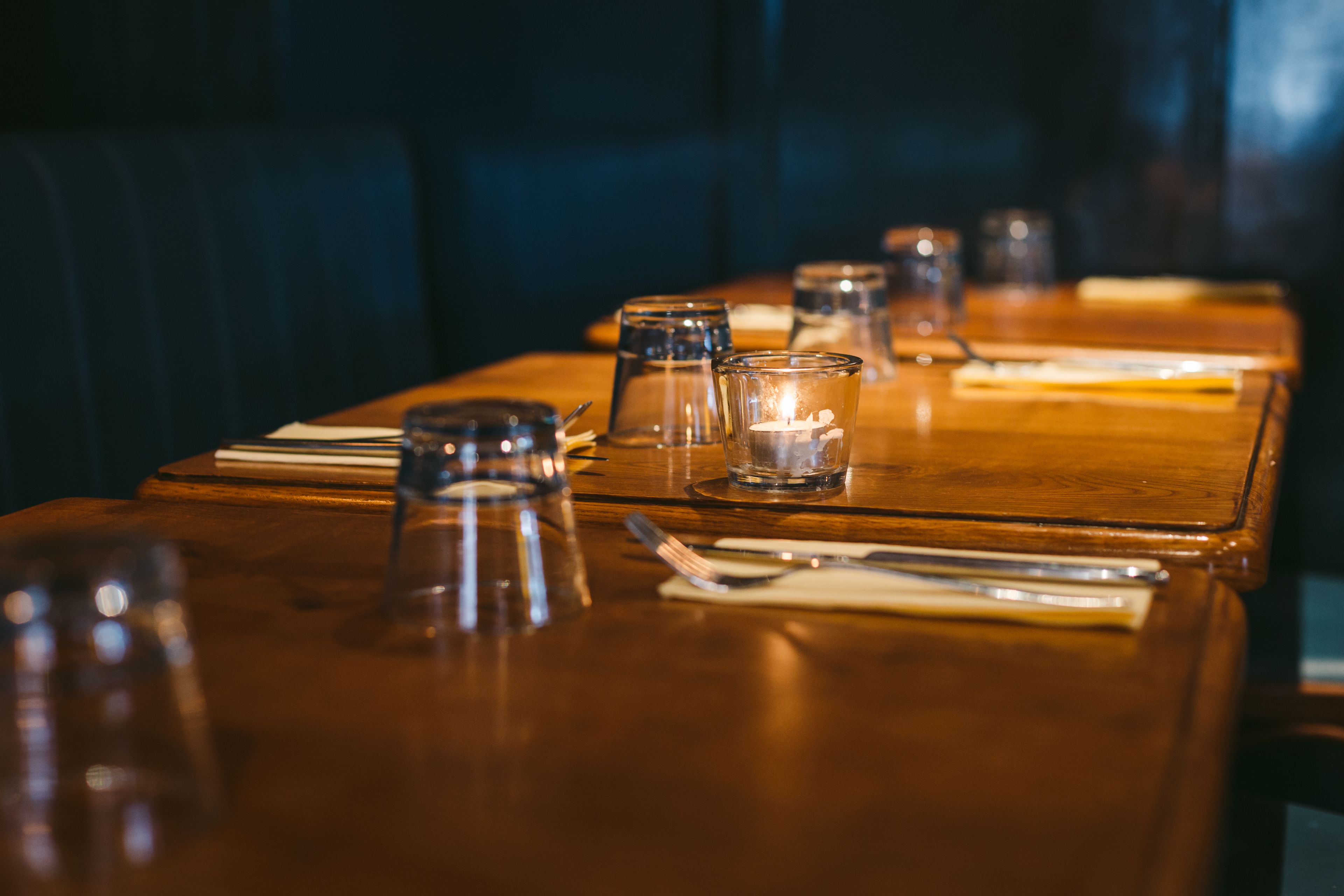 A restaurant table set with clear glasses, cutlery, and napkins.