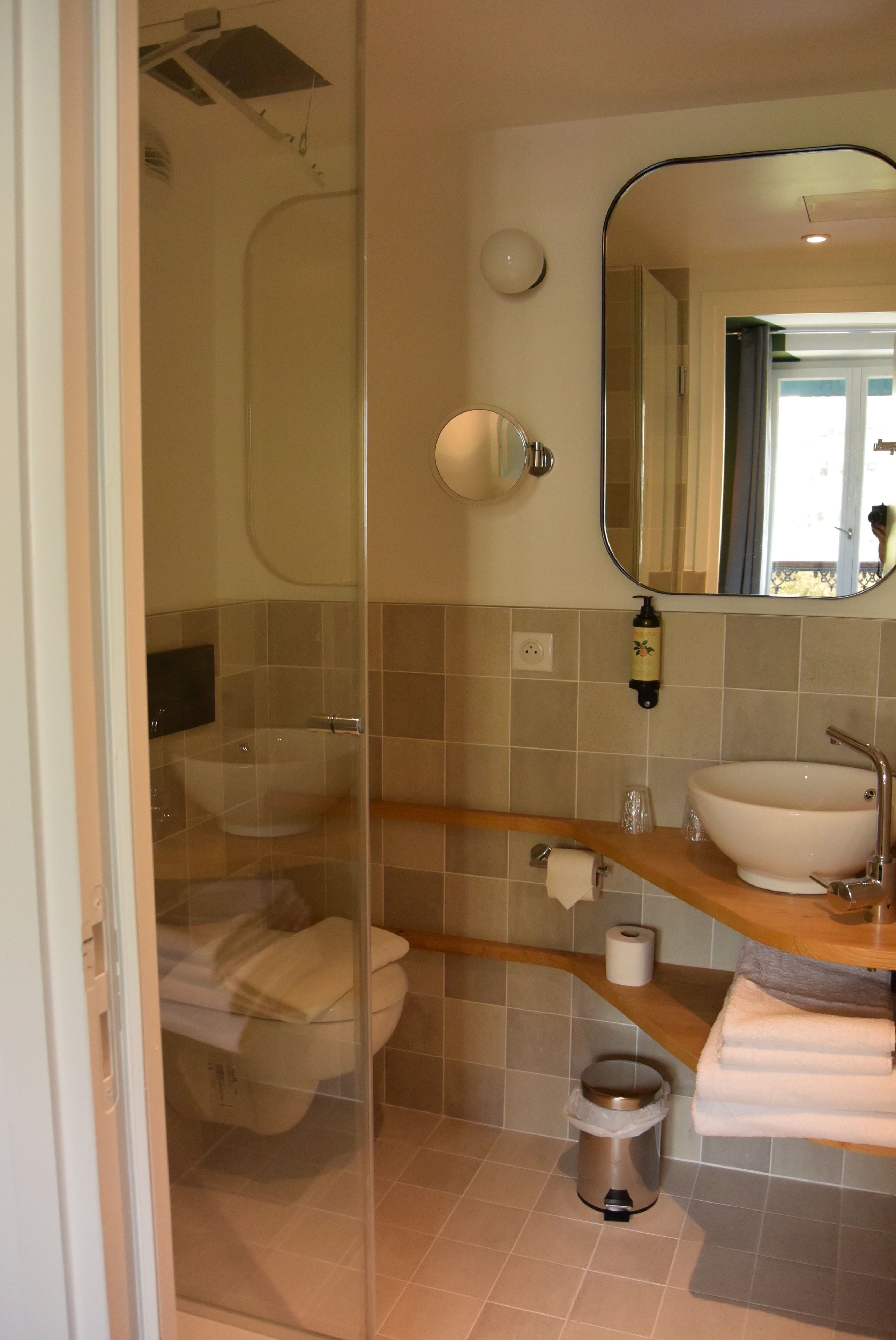 A modern bathroom with a glass-enclosed shower, a white sink, a mirror, and a toilet.