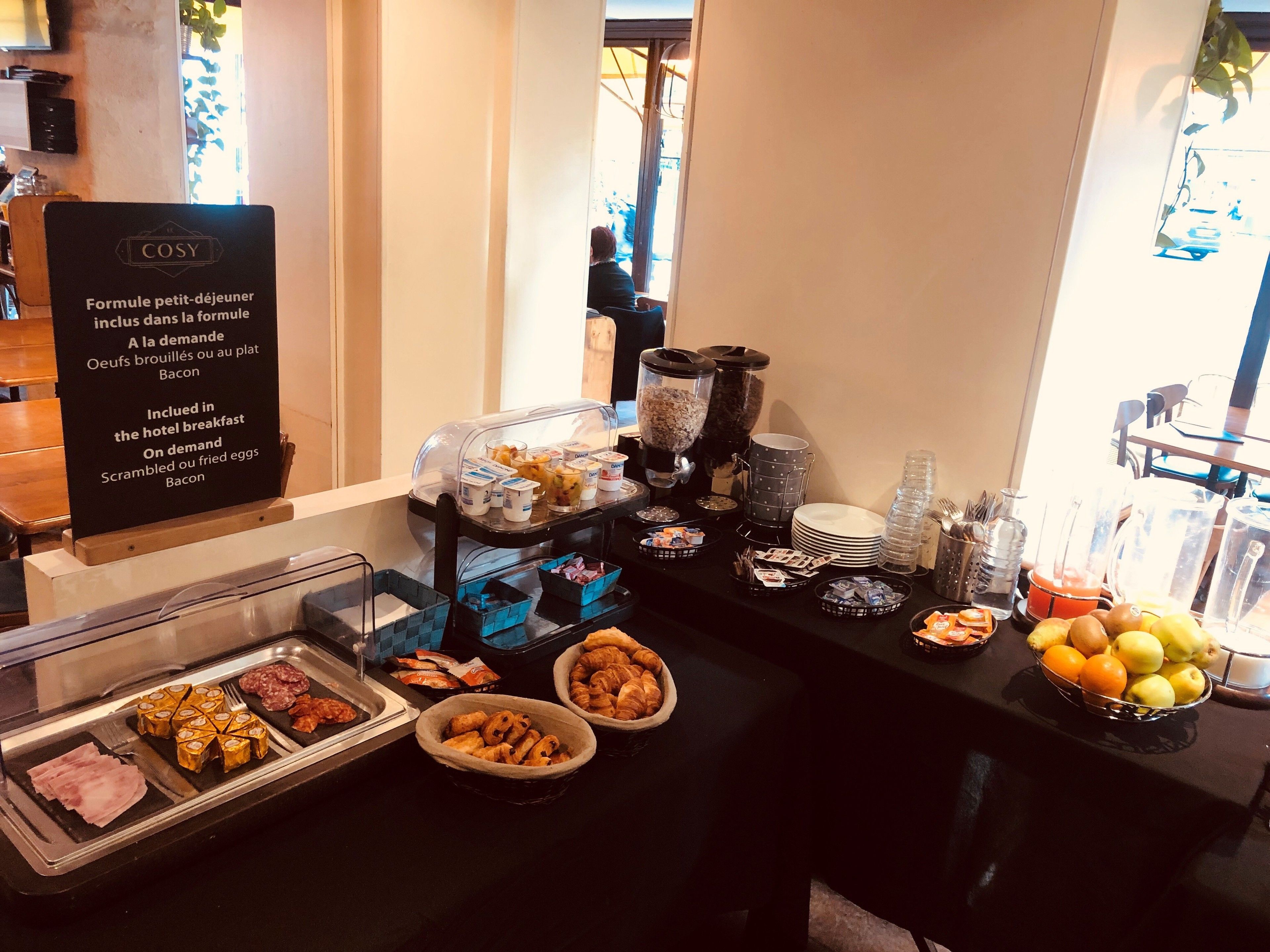 Un buffet de petit-déjeuner d'hôtel proposant une variété d'aliments, accompagné d'un panneau indiquant les différentes options disponibles.