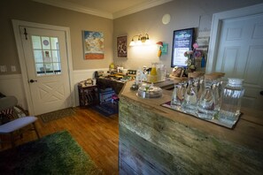 A kitchen with a wooden counter, a sink, and various kitchen items. There is a door with a window, a chair, and a rug on the floor.