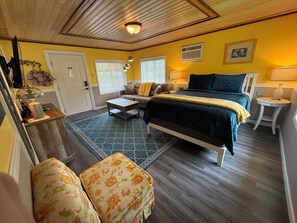 A bedroom with a bed, a sofa, a coffee table, and a lamp.