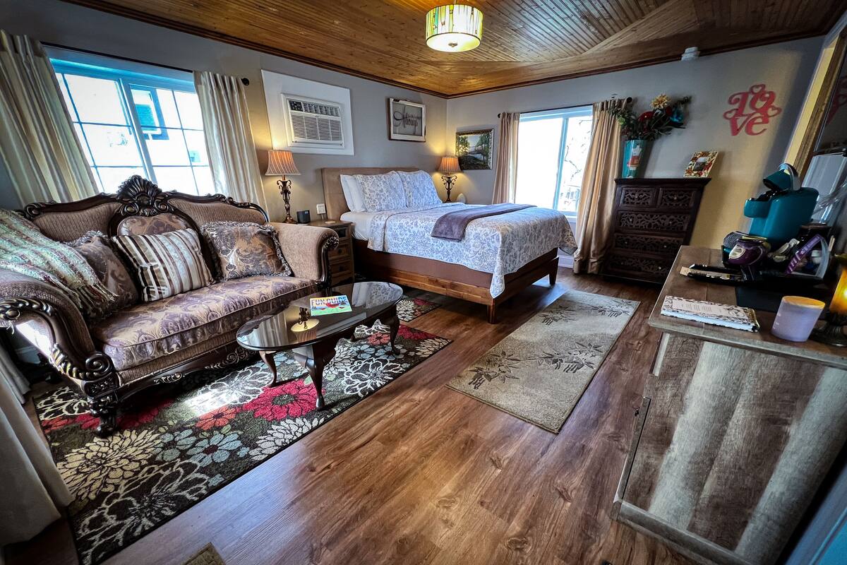 A cozy living room with a sofa, a coffee table, a bed, and a wooden cabinet.