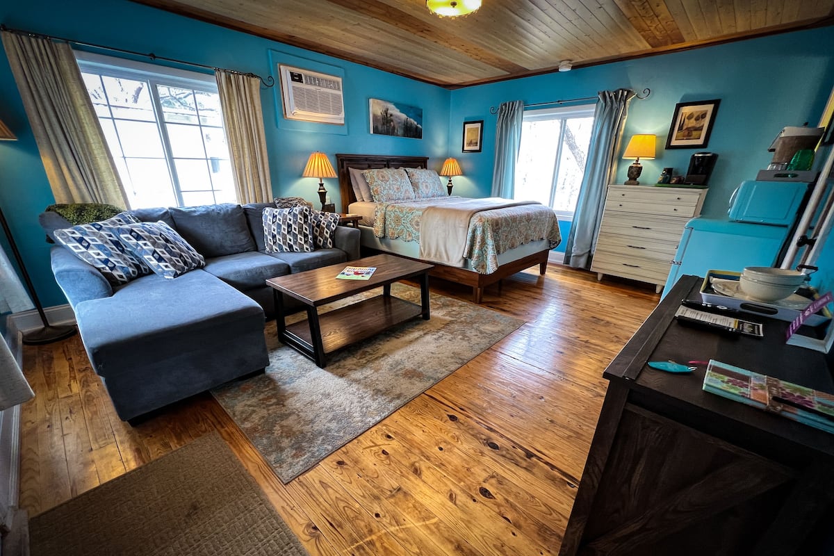 A cozy room with a sofa, a bed, a coffee table, and a dresser.