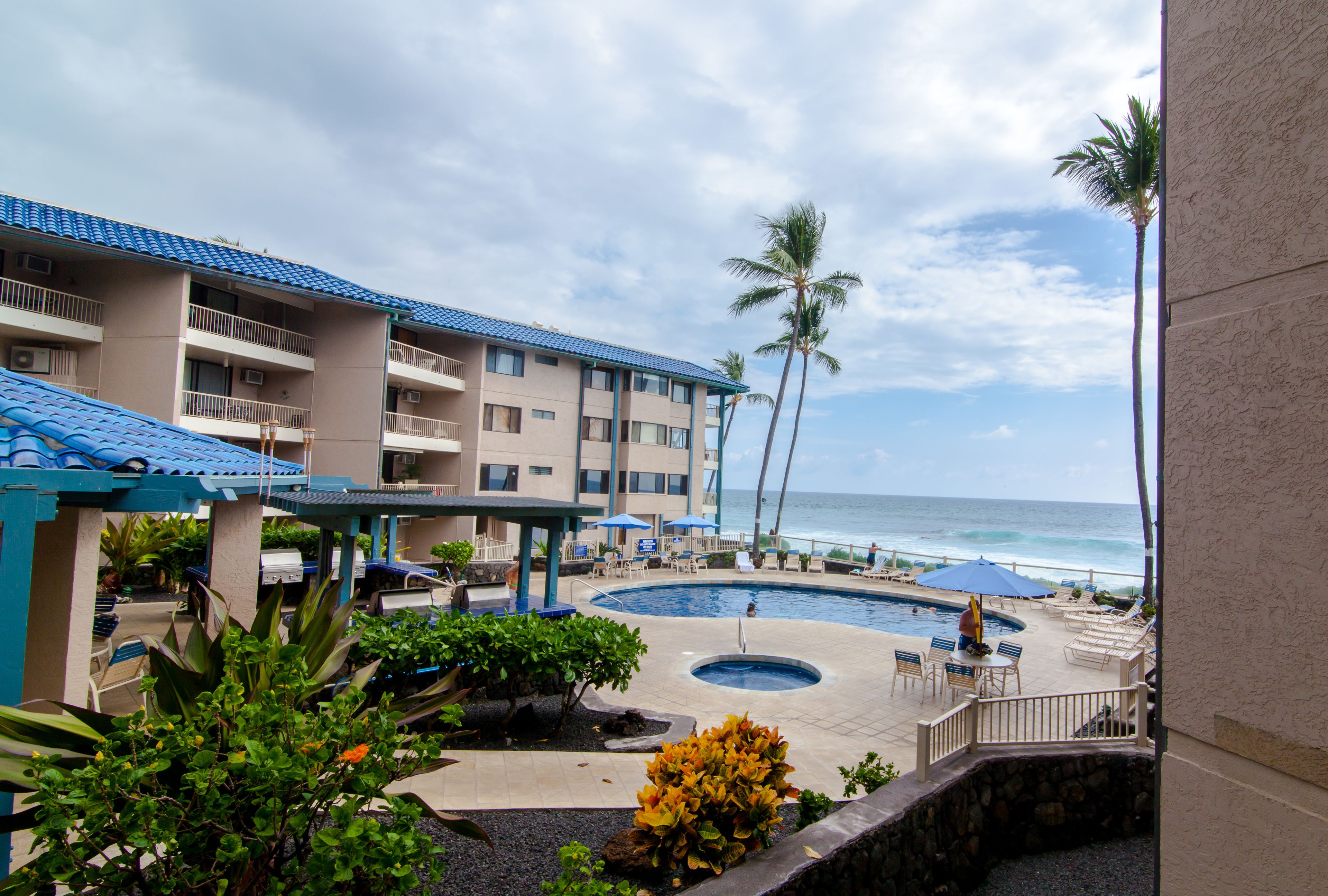 A hotel with a pool area, lounge chairs, and a view of the ocean.