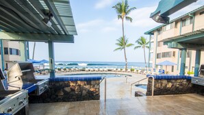 An outdoor pool area with a stone wall, a grill, and lounge chairs. - Kona Reef, A Raintree Vacation Club Resort (Kailua-Kona)