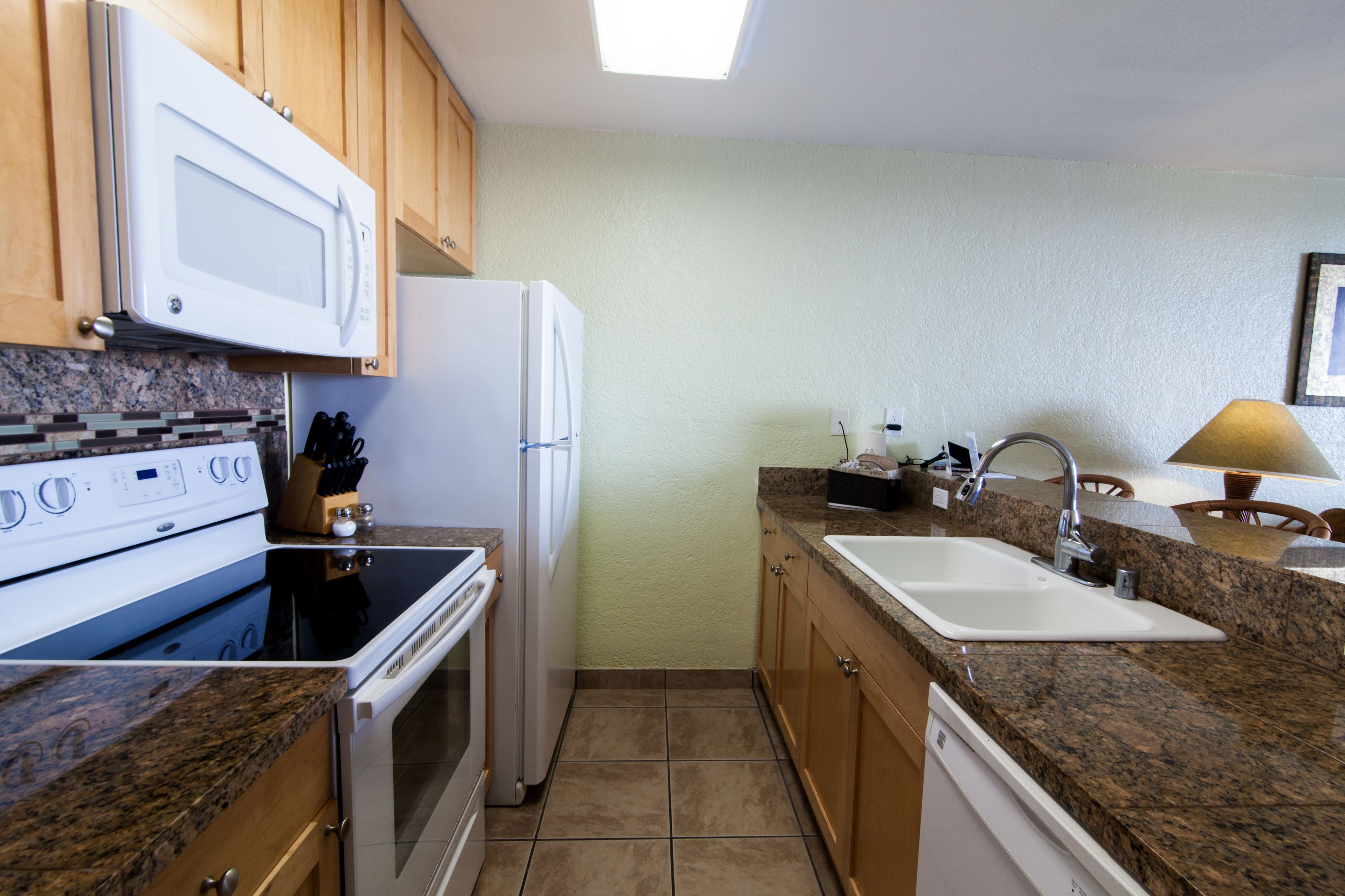 A kitchen with granite countertops, white appliances, and wooden cabinets.