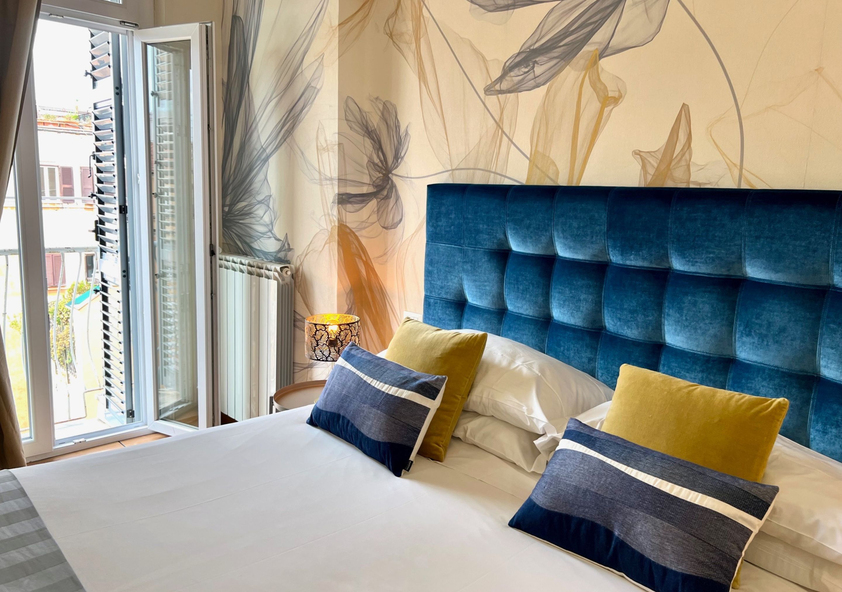 A bedroom with a large bed, a blue headboard, and a view of the outside through a sliding door.