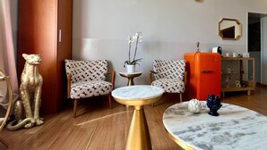 A modern living room with patterned chairs, a round gold table, a red vintage refrigerator, and decorative items. - Bon Ton Design Rooms by DOT Suites (Rome)