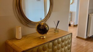 A wooden console table with a globe, a mirror, and a small vase with reed sticks. - Bon Ton Design Rooms by DOT Suites (Rome)