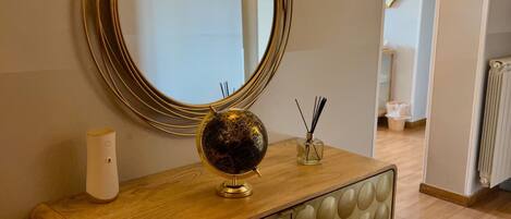 A wooden console table with a globe, a mirror, and a small vase with reed sticks.