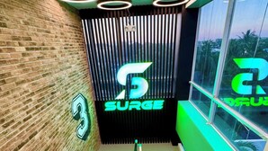 Un escalier moderne aux couleurs vert et blanc, un logo avec le chiffre 5 et une enseigne sur laquelle on peut lire « SURGE ».