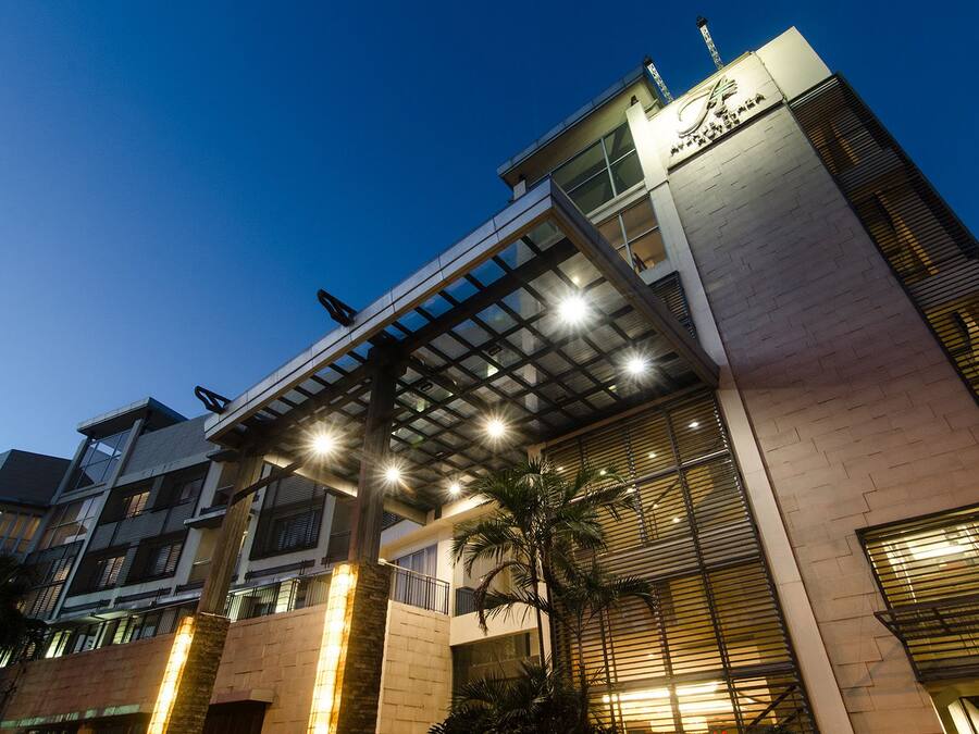 Un hotel moderno con entrada cubierta, varios pisos y un cartel llamativo.