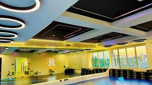 Une salle de sport avec des murs recouverts de miroirs, un comptoir d’accueil et une vue sur l’extérieur.