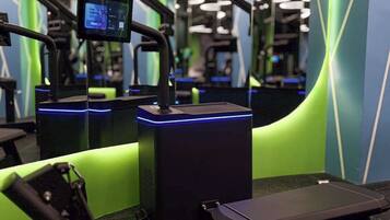 Un gimnasio con equipo de ejercicio, una pantalla digital y un espejo.
