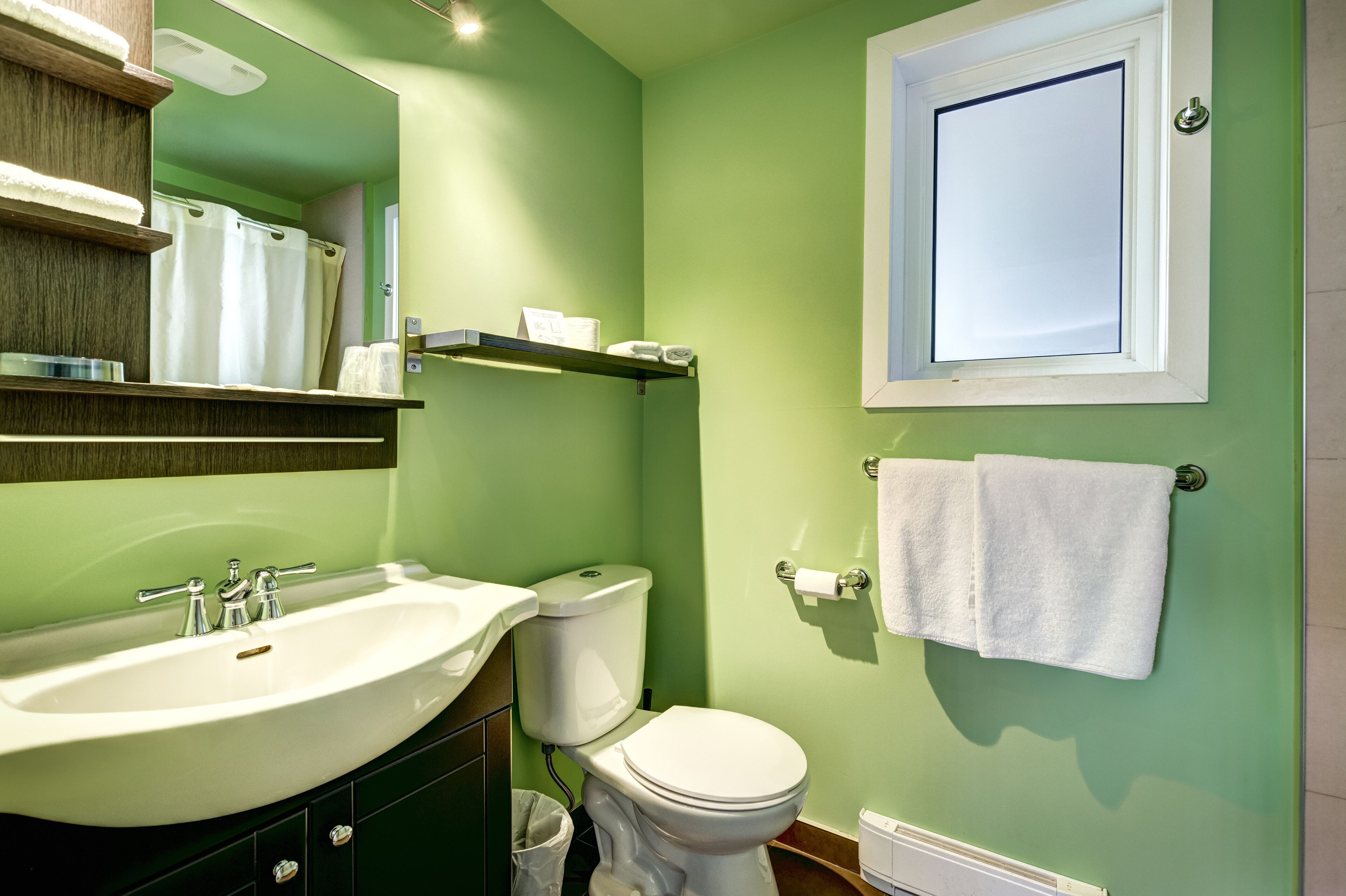 Un baño con lavamanos, inodoro y espejo.