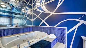 Un baño moderno con una bañera grande, paredes de azulejos azules y un diseño geométrico.