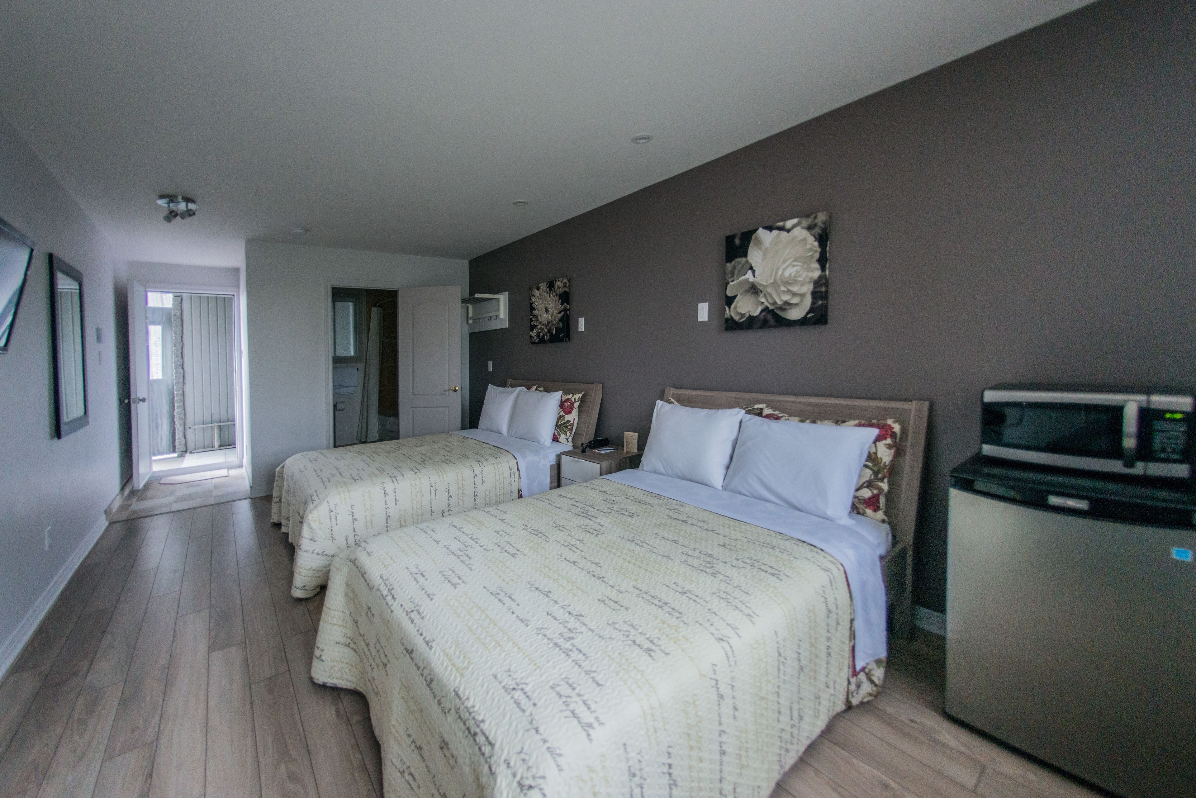 A hotel room with two beds, a refrigerator, and a microwave.