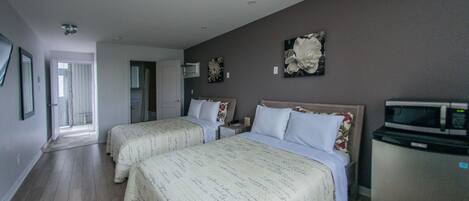 A hotel room with two beds, a refrigerator, and a microwave.