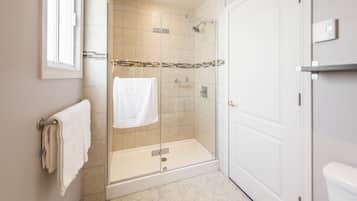 A modern bathroom with a glass-enclosed shower, a white toilet, and a towel rack.