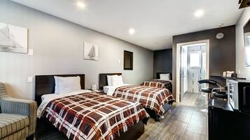 Habitación de hotel con dos camas, una silla, un escritorio y un kitchenette.