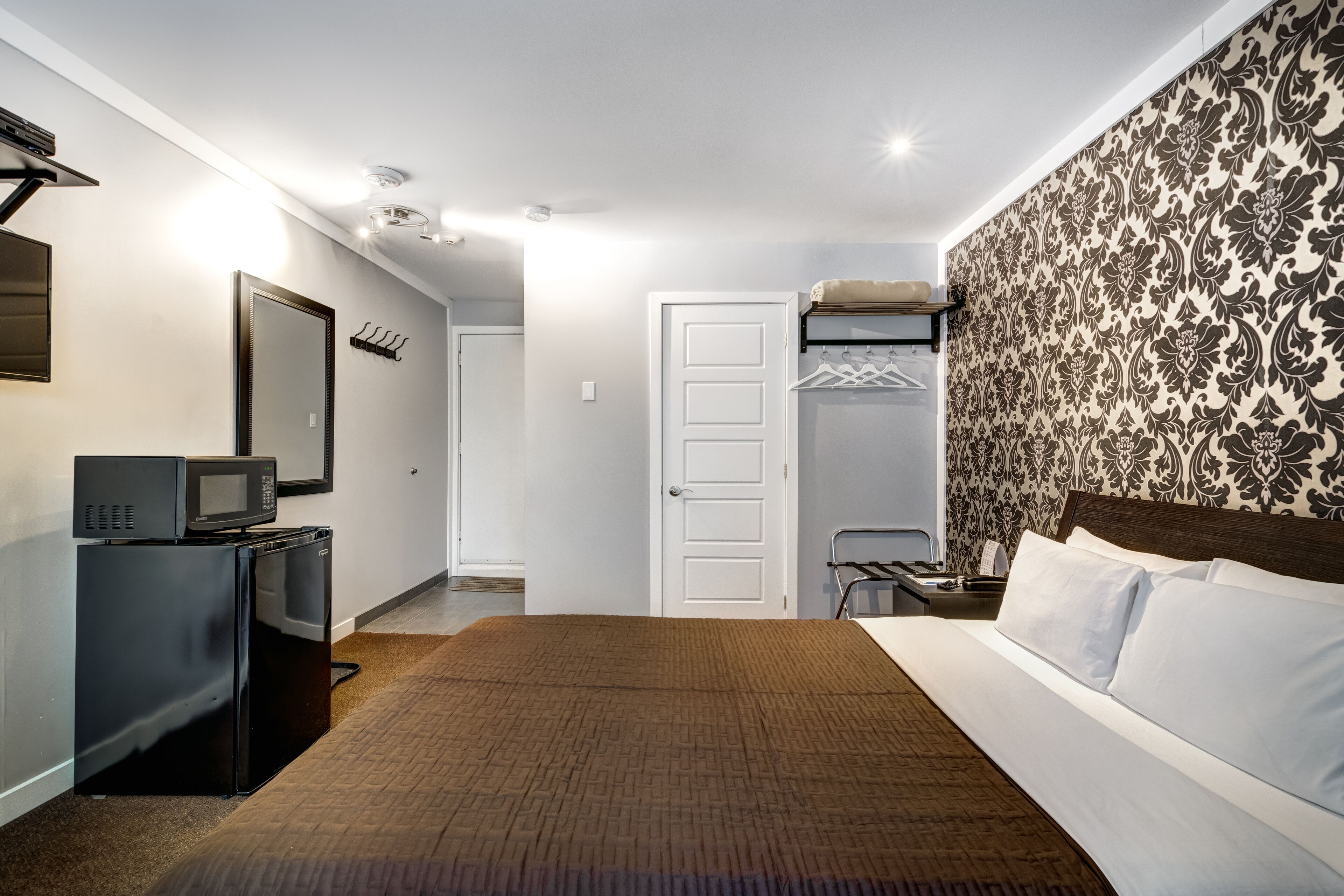 Ein Hotelzimmer mit einem Bett, einem Schrank, einer Mikrowelle und einem kleinen Tisch.