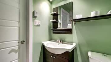 Un baño con lavamanos blanco, muebles oscuros, un espejo y un inodoro.