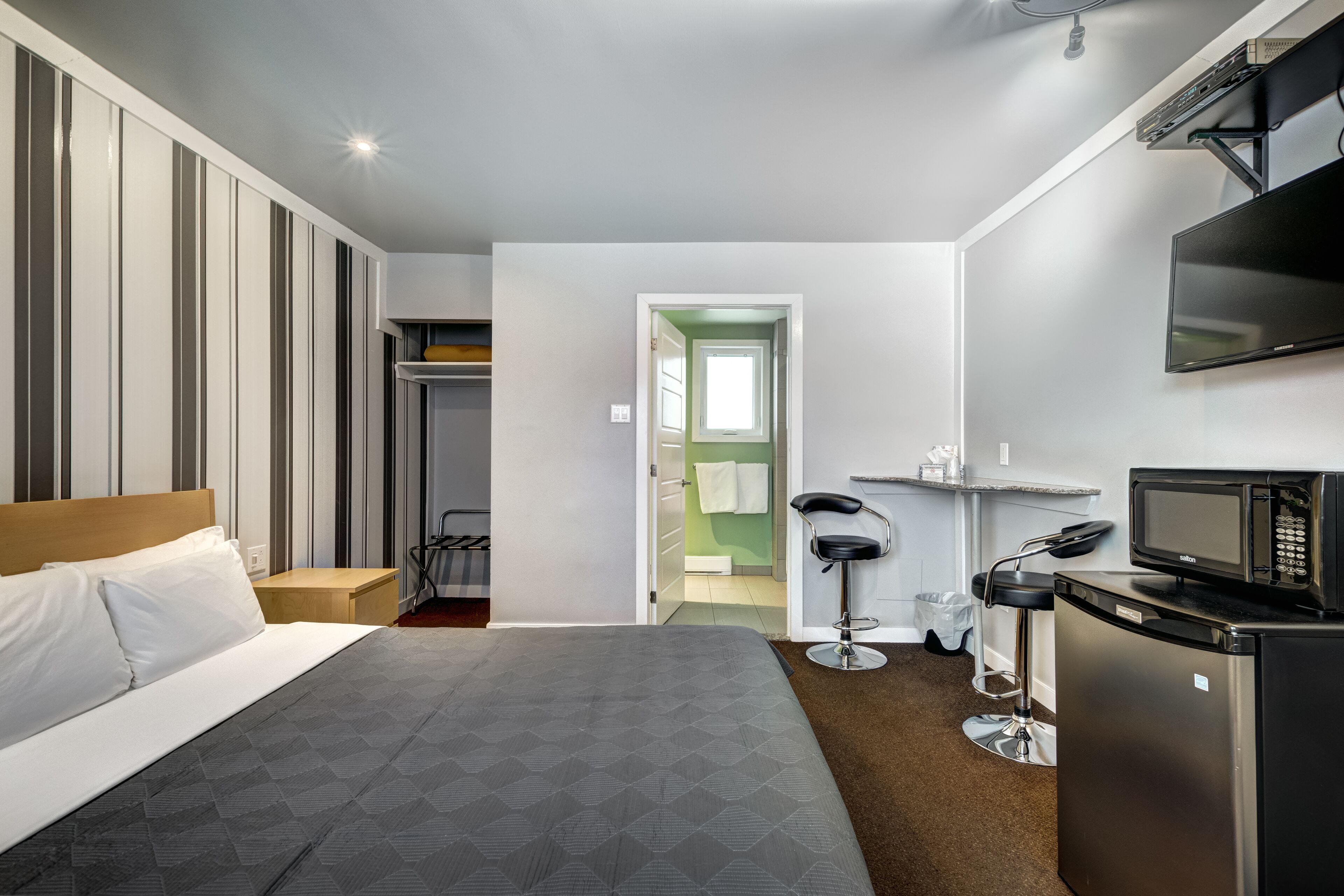 A hotel room with a bed, a TV, a microwave, and a small kitchenette.
