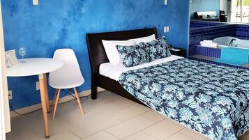 Une chambre moderne avec un grand lit, une petite table blanche et une chaise.